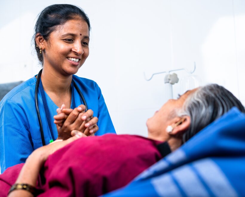 Indian nurse assisting an elderly patient at home